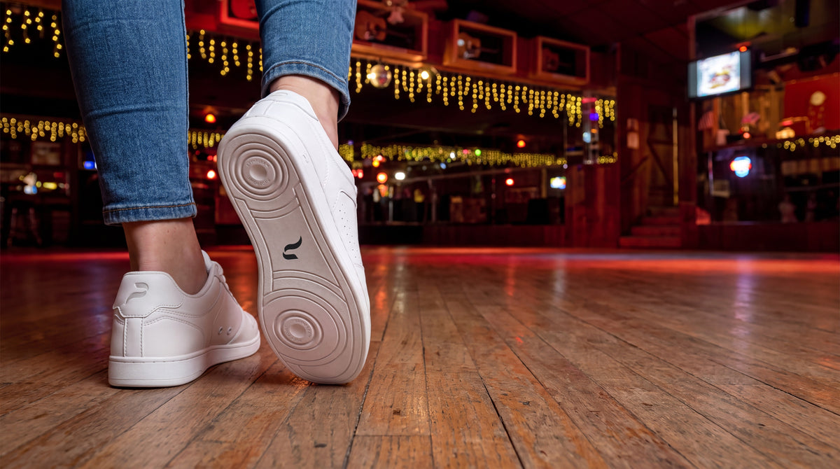 A line dancer walking onto the dance floor of a country bar in Pulse Dance Shoes Flow 2 White dance sneakers